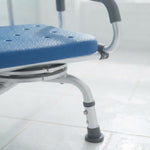 Close-up of a portable shower seat with a blue textured cushion and silver metal frame, shown on a tiled floor.
